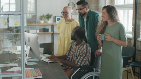 African-American-Man-in-Wheelchair-Working-with-Business-Team-in-Office